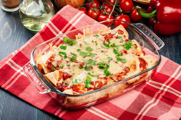 Traditional mexican enchiladas with chicken meat, spicy tomato sauce and cheese in heat resistant dish