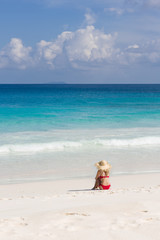 Colorful ocean beach, slim woman in red swimsuit and straw sun hat