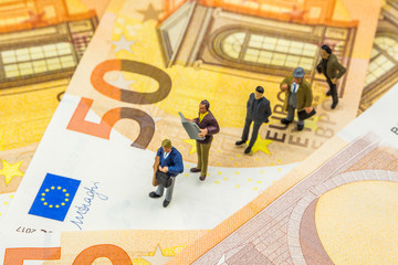 little figurines standing in line on new 50 euro banknotes