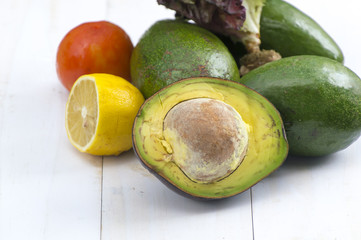 Avocado and avocado pieces on a wooden floor and has a background of nature; Selected focus