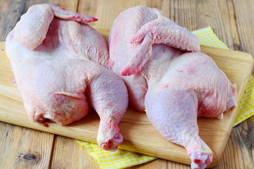 Two halves of raw chicken on a wooden cutting board. Cooking step by step. Healthy eating concept