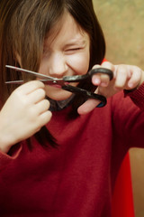 Obraz premium girl narrowing eyes from fear while cutting hair