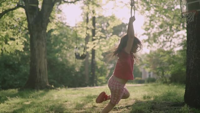 Little girl hang on sports rings at playground in house yard slowmotion 4k