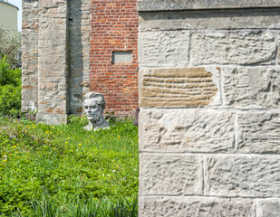 Head of statue in the grass near the old church of red brick