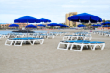 Fototapeta na wymiar Sunbeds and umbrella a beautiful beach. Modern blurred image. Abstract blur vacation background.