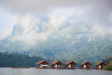 Floating houses on the lake with mountain background in a cloudy day.