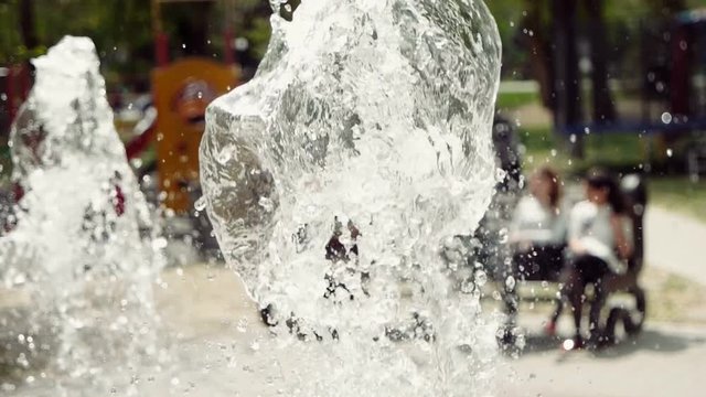 Slow motion water splashing on foreground and children having fun on blurred background