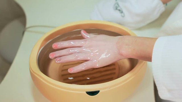 Process paraffin treatment of female hands in beauty salon