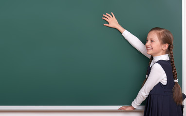 elementary school girl put hands on chalkboard background and show blank space, dressed in classic black suit, group pupil, education concept