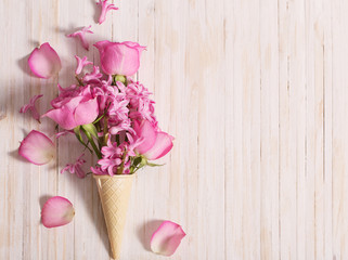 Flowers in a waffle cone on white wooden background