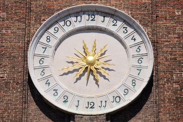 Ancient clock of Saints Apostles church in Venice with golden sun hands in the center