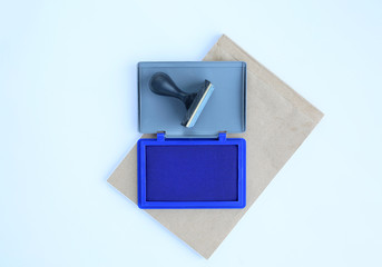 Rubber stamp and Blue Ink cartridges on brown book against white background.