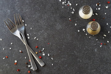 Grey abstract background with forks, salt and pepper shakers. Place for text