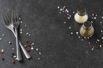 Grey abstract background with forks, salt and pepper shakers. Place for text
