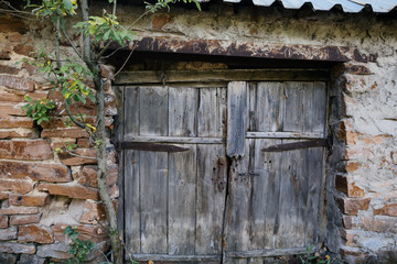 Old wooden gate doors and stone wall