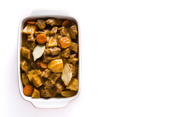 Beef meat stewed with potatoes, carrots and spices in ceramic pot isolated on white background.Top view
