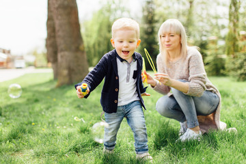 Fototapeta premium Little boy do bubbles with his mother at park