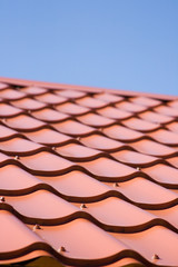 Red roof of metal roofing on the sky background