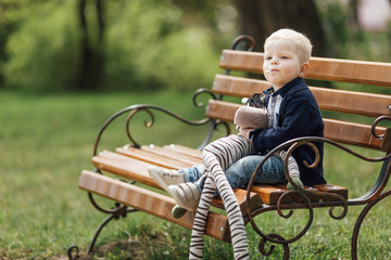 Little boy sit on the bench with his toy