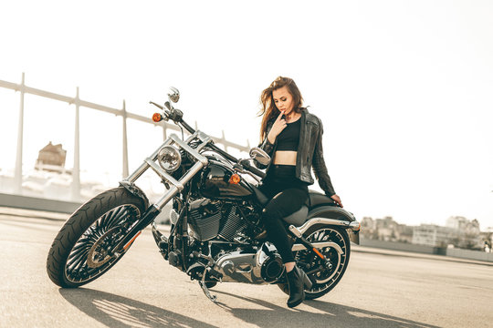 Girl on a motorcycle. She is beautiful, posing on a motorcycle at sunset