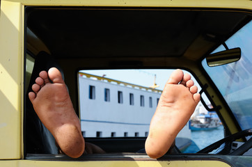 Feet of the Indonesian driver resting in his car during several days' expectation of the ferry to the next island