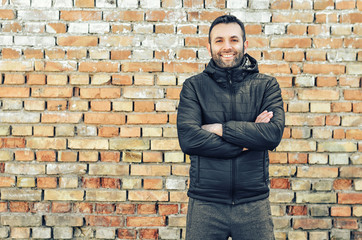 Fototapeta na wymiar Close up portrait of happy man with beard smiling standing near a brick wall