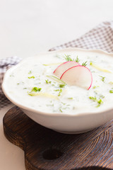 Yoghurt cold soup with radish, cucumber and dill on wooden board. Traditional soup tarator with radish and cucumber. Cold summer soup - okroshka. Healthy eating. Clean eating