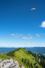 Brauneck Gipfel mit Gleitschirmflieger und blauem Himmel