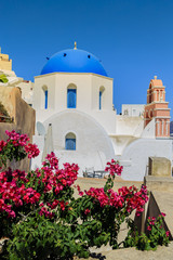 Picturesque view of Old Town of Oia on the island Santorini, white houses, windmills and church with blue domes, Greece