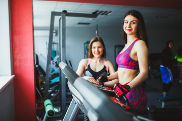 Woman with personal trainer exercising on treadmill in gym