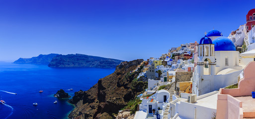 Malerische Aussicht auf die Altstadt von Oia auf der Insel Santorini, weiße Häuser, Windmühlen und Kirche mit blauen Kuppeln, Griechenland