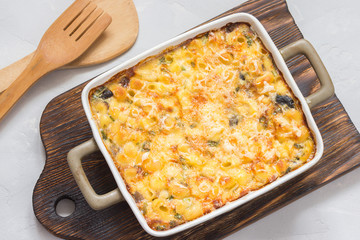 Macaroni and cheese in a backing dish on wooden board. Top view.