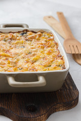 Macaroni and cheese in a backing dish on wooden board. 