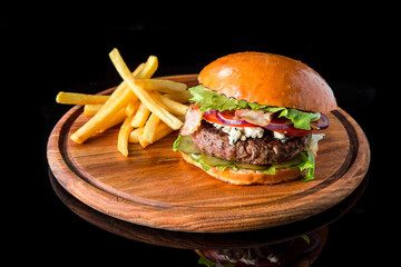 Cheeseburger with french fries on a wooden board.