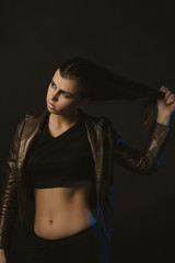 Attractive young  woman in leather jacket pulling her hair