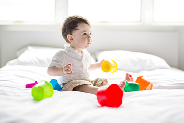 baby lying in the bed on white blanket. Cute boy playing with cubes