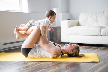 sports mother is engaged in fitness and yoga with a baby at home
