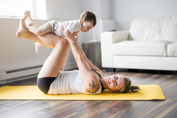 Fototapeta na wymiar sports mother is engaged in fitness and yoga with a baby at home