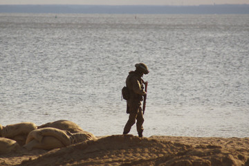 Military soldier on the beach near the water's edge