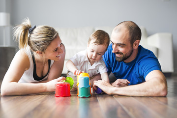 Happy family with parents and son playing with colorful blocks in the livingroom