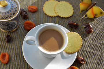 white  сup with coffee, crackers and dried fruits on a beige napkin