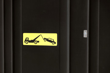 Yelow sign on black garage door - traffic sign - no parking, tow away zone sign