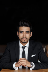 handsome confident young man in suit sitting in cafe, hands on the table.