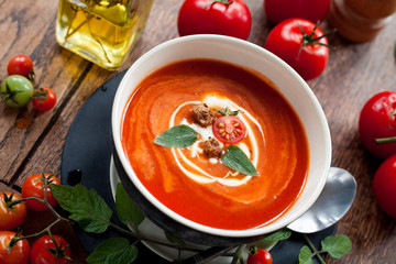 Fresh homemade Tomato Soup with herbs and croutons. Creamy healthy vegetarian lunch. All decorated with fresh tomatoes and olive oil.