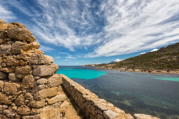 Fototapeta na wymiar Stone wall of derelict building and translucent sea in Corsica
