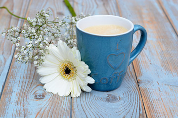 Obraz na płótnie Canvas Blue coffee cup on a grey old wooden background with a white gerber daisy flower 