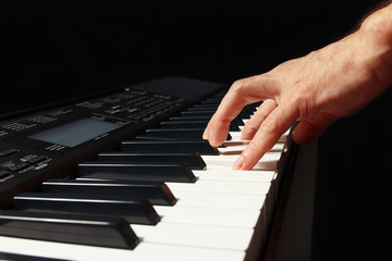 Obraz premium Hand of pianist playing the electronic synth on a black background