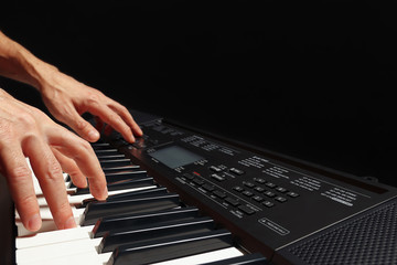 Fototapeta premium Hands of pianist play the keys of the synthesizer on a black background