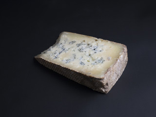 Slice of french blue cheese made from cows milk isolated on black background