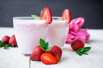 Strawberry smoothie with strawberry and flowers on white wood background. Flat lay. Top view. Fresh milkshake
